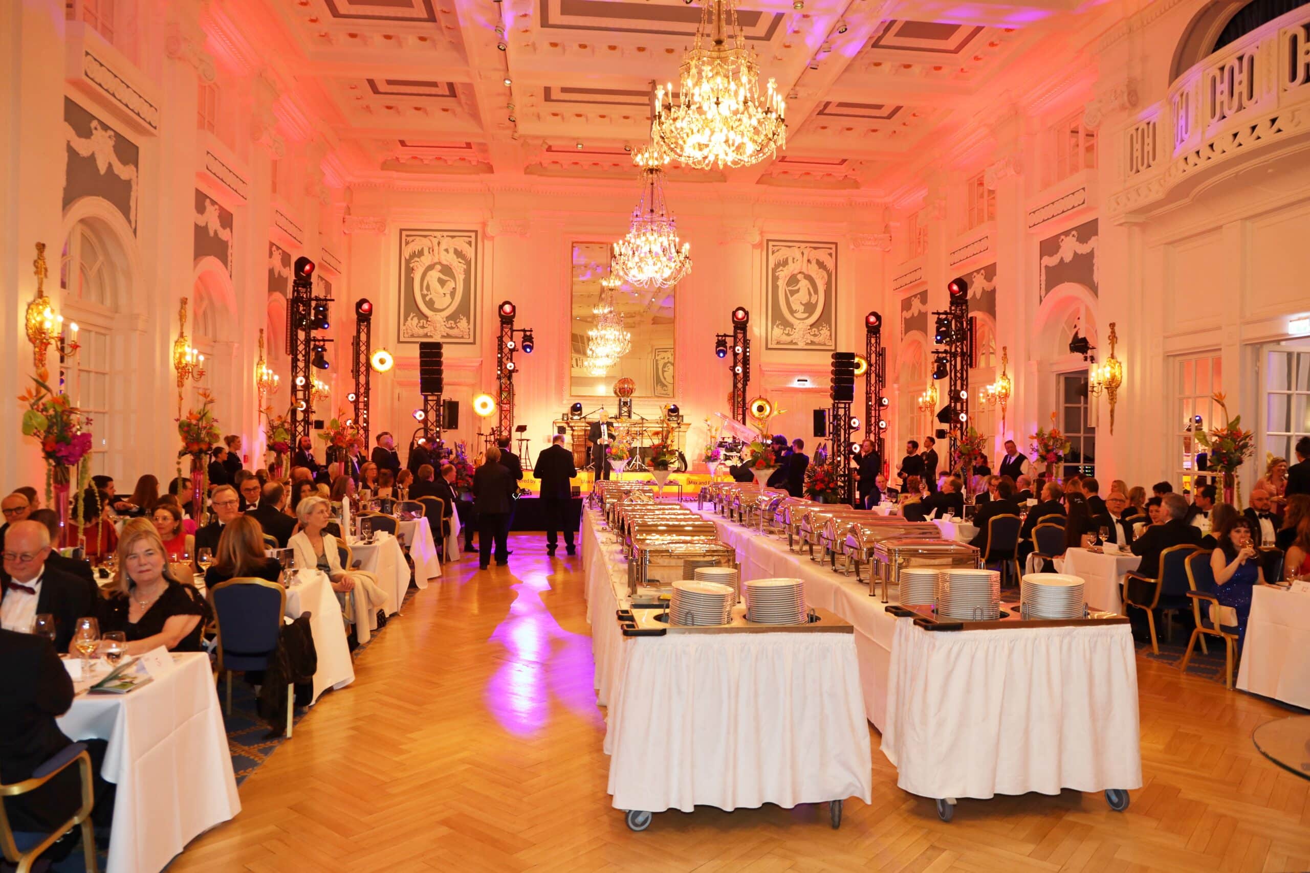 Festlich gedeckter großer Festsaal im Hotel Atlantic während des Hamburger Presseballs mit Gästen und Bühnenbeleuchtung.