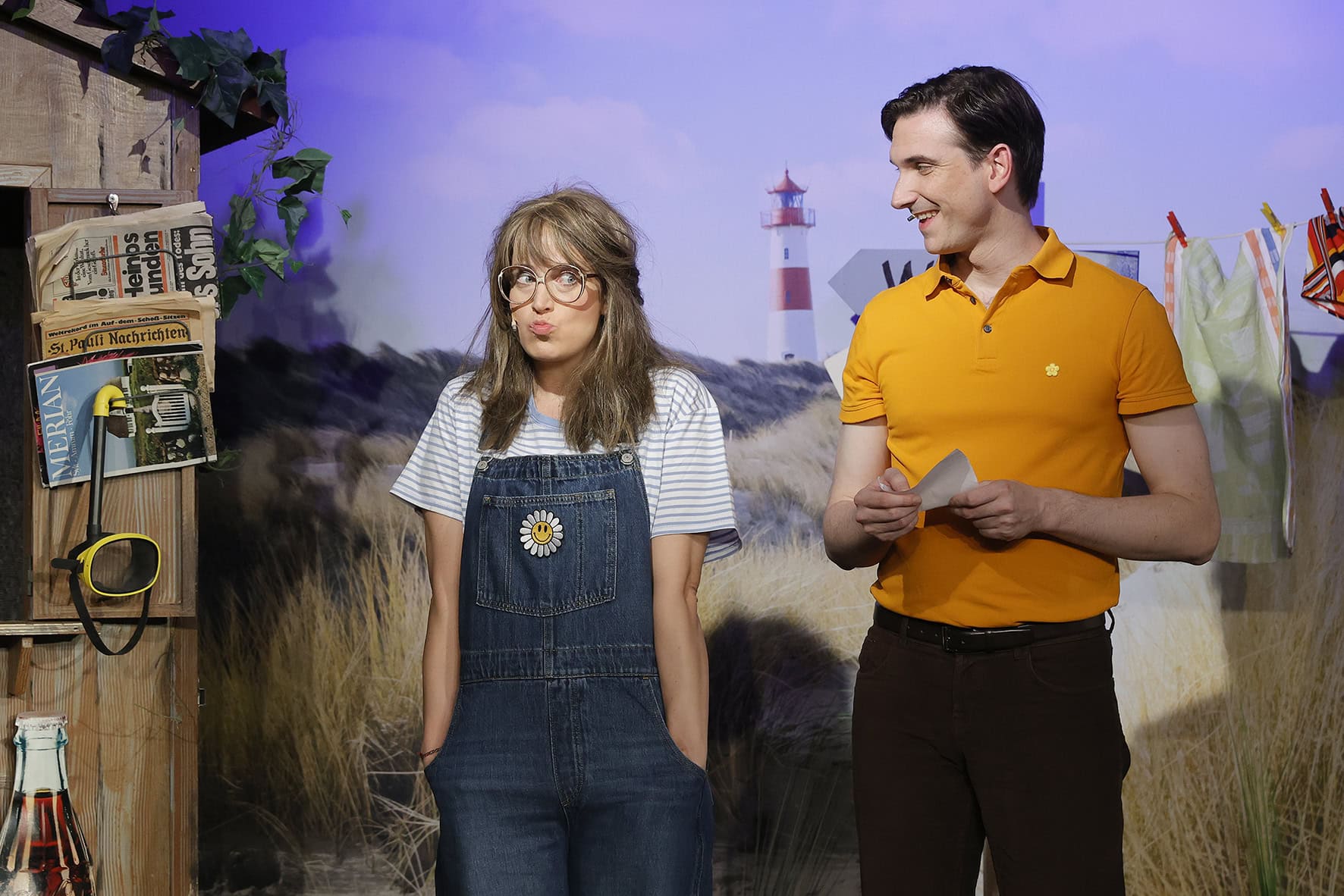 Szene aus „ABER BITTE MIT SCHLAGER“ im Neues Theater Hannover: Vor Dünen- und Leuchtturm-Kulisse treffen jugendliche Schwärmerei und 70er-Jahre-Charme aufeinander – mit augenzwinkerndem Spiel und viel Nostalgie rund um den fiktiven Ostsee-Campingplatz. Foto: Oliver Vosshage